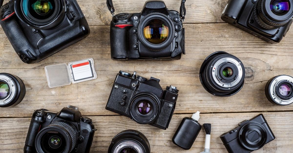 A Collection Of Cameras And Accessories Arranged On A Wooden Table.