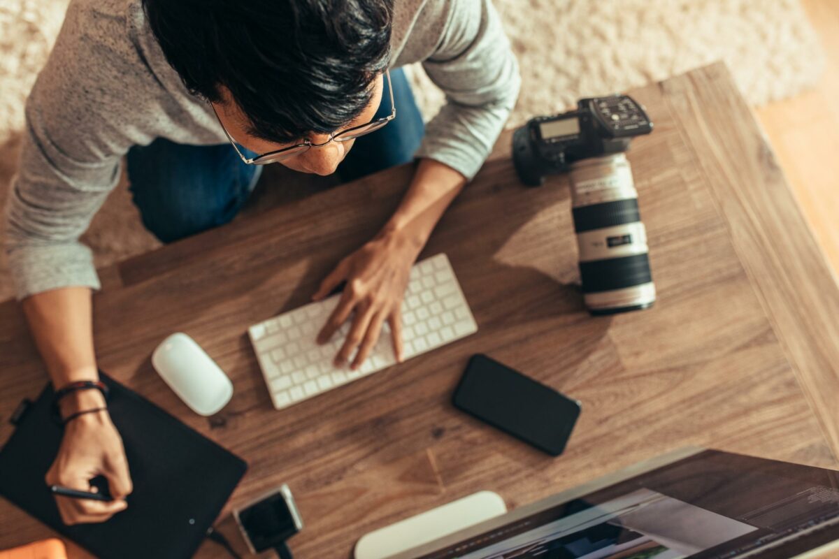 A Man Working At A Desk With A Laptop, Performing Photo Editing For Beginners.