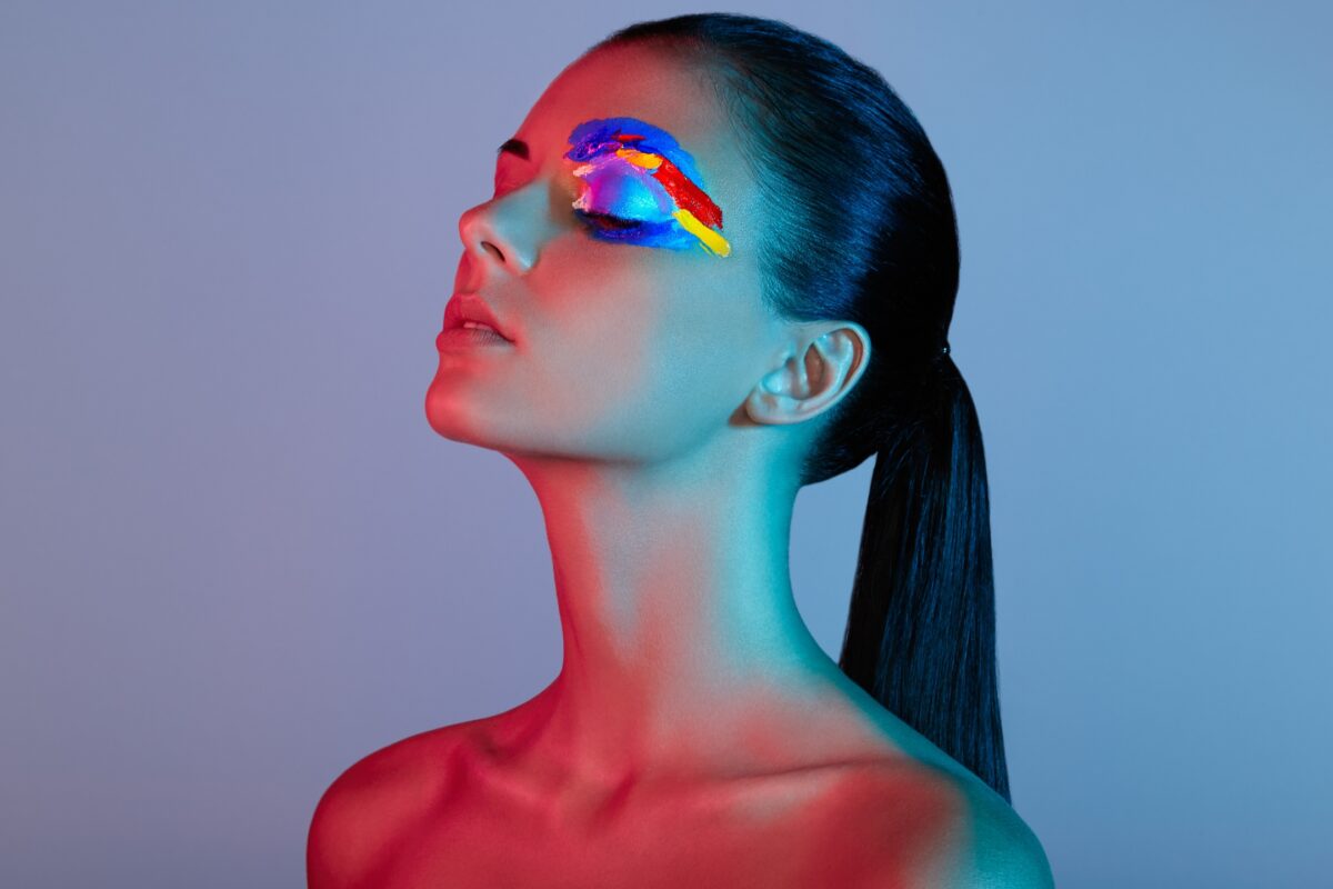 A Woman With Vibrant Makeup On Her Face Striking Various Poses During A Photo Session.