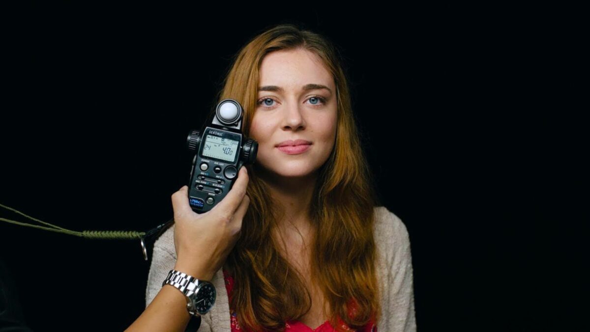 A Woman Is Holding A Cell Phone In Front Of A Black Background, With Photography Lighting Enhancing The Scene.