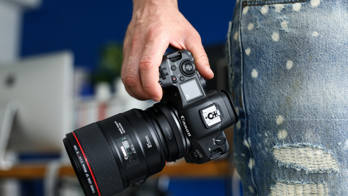 A Person Holding A Dslr Camera In Their Jeans.