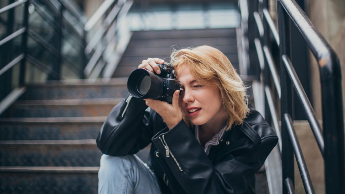 A Woman Taking A Picture With Her Camera On The Stairs.