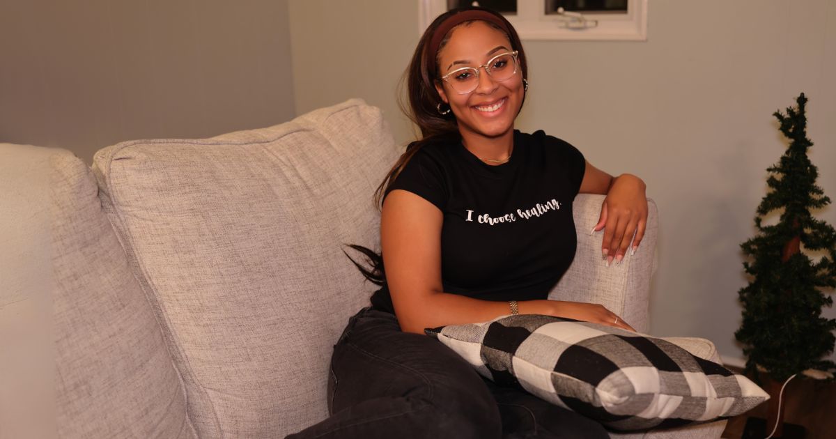 A Woman Sitting On A Couch With A Pillow In A Home Photography Session.