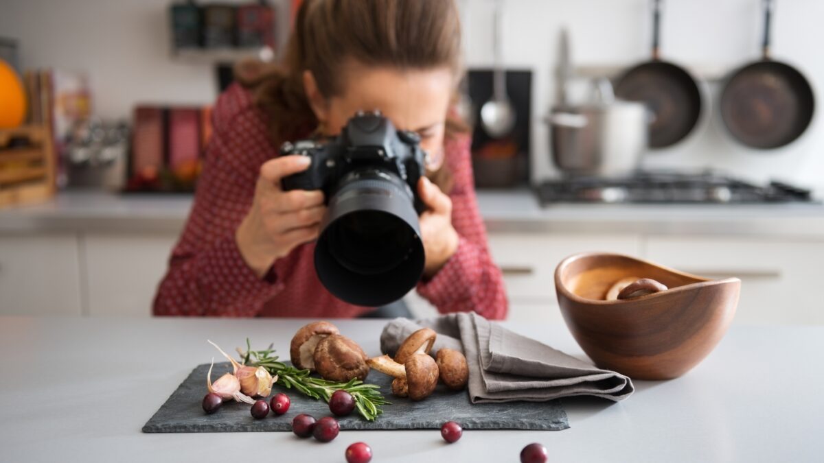 A Woman Is Capturing Perfect Indoor Photos Of Food With A Camera.