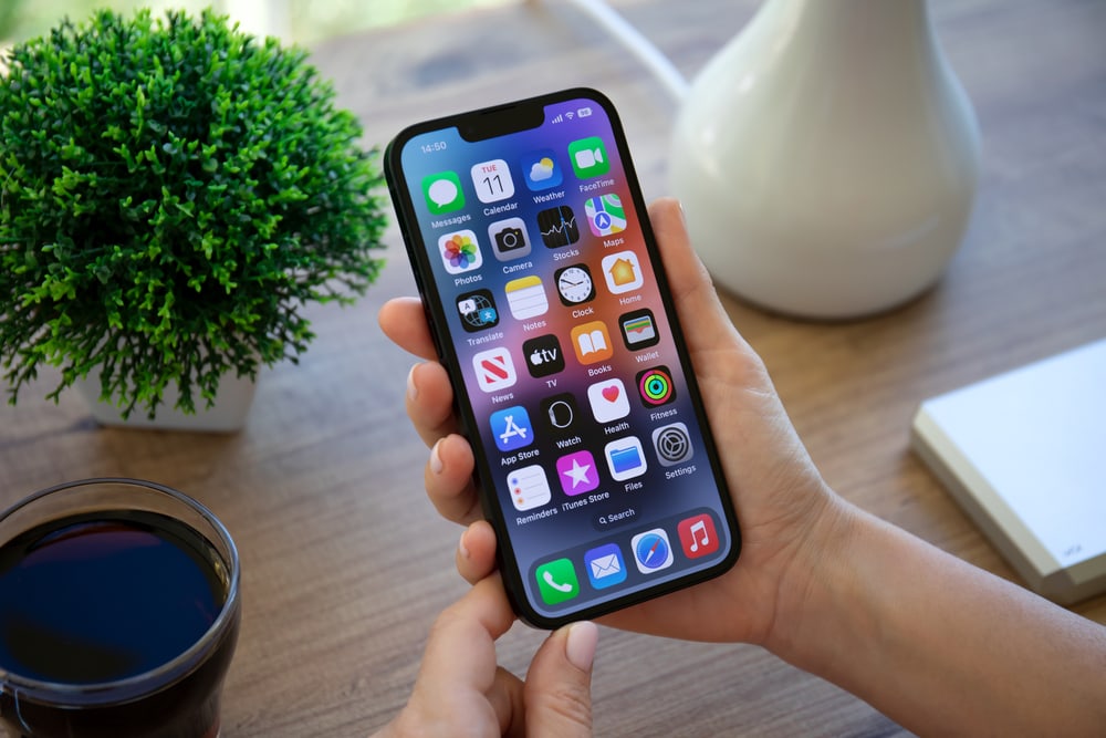 A Person Using An Iphone X To Capture A Modern-Day Photograph Next To A Cup Of Coffee, Reflecting The Continued Evolution Of Photography.