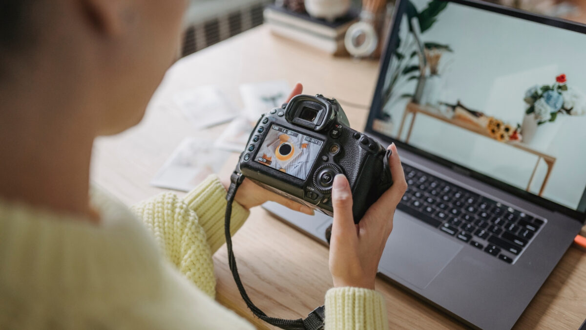 A Woman Is Using Her Dslr Camera To Store And Backup Photos On A Laptop.